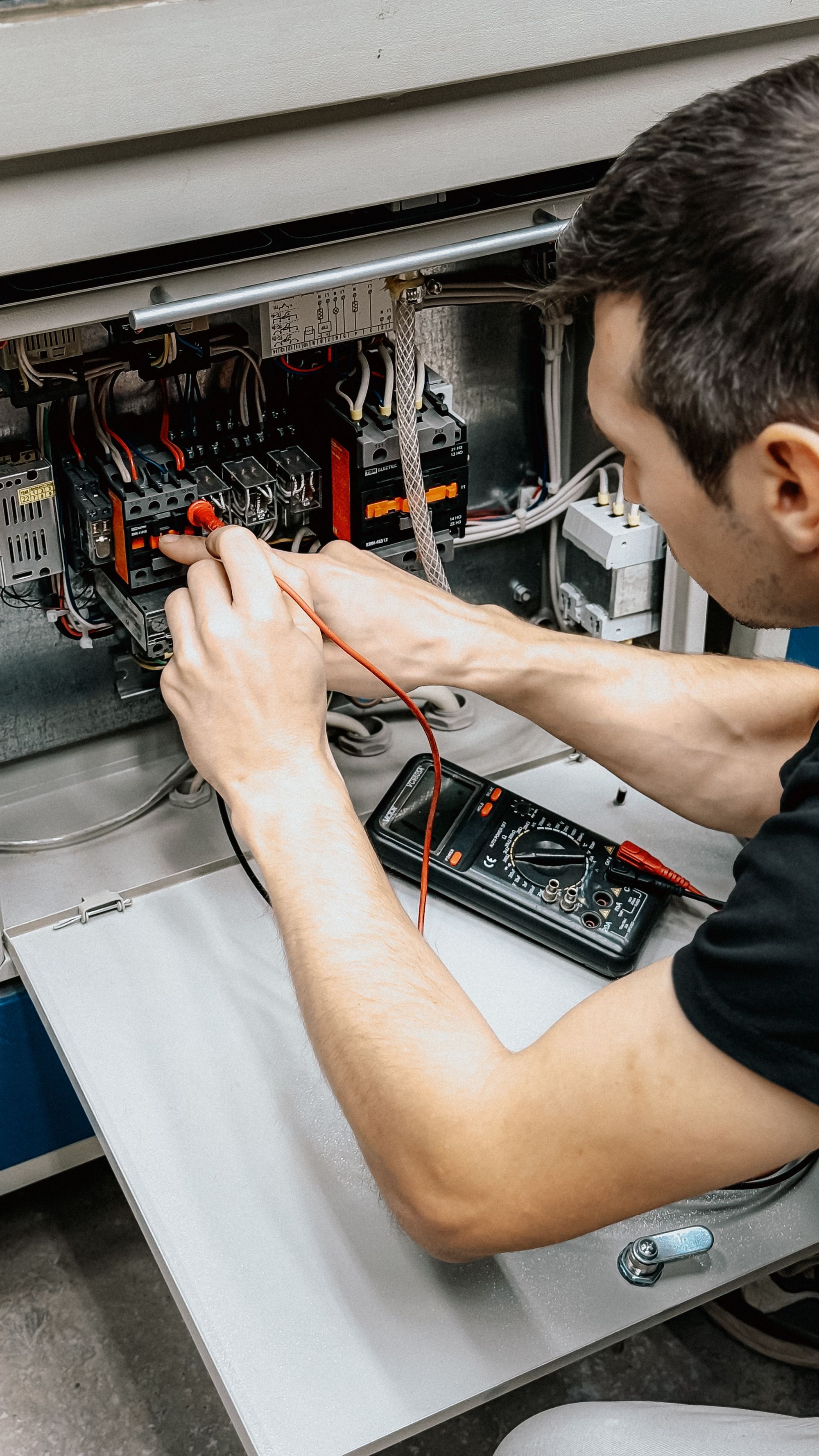 Elektryk sprawdza miernikiem połączenia w otwartej rozdzielnicy